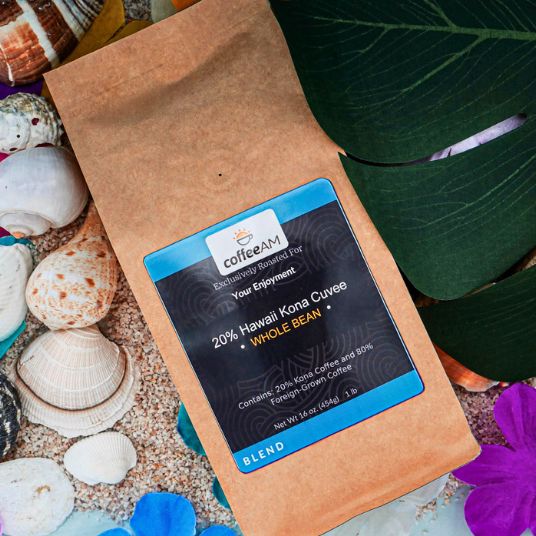 Coffee bag labeled 'coffeeM' with a 20% Hawaii Kona Cuvee blend on a natural background with shells and plants.