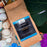 Coffee bag labeled 'coffeeM' with a 20% Hawaii Kona Cuvee blend on a natural background with shells and plants.