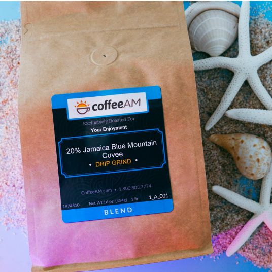 CoffeeAM Jamaica Blue Mountain Cuvee coffee package on a beach-themed background with shells and sand.