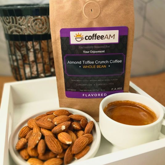 CoffeeAM Almond Toffee Crunch coffee package with a cup of coffee and almonds on a tray.