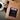 A brown kraft-paper coffee bag labeled "coffeeAM Angel Face Coffee, WHOLE BEAN, FLAVORED" sits on a grey tabletop on top of a light brown cutting board. Positioned nearby are a white ceramic coffee cup on a saucer, scattered whole coffee beans, gold spoon, and decorative woven rattan spheres.