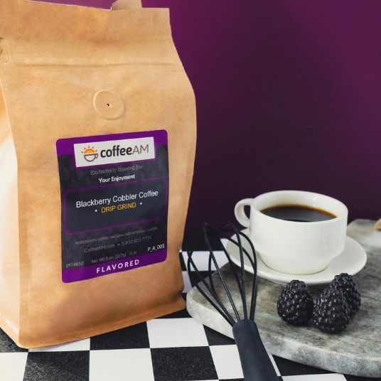 CoffeeAM Blackberry Cobbler coffee package with a cup of coffee and blackberries on a checkered tablecloth.