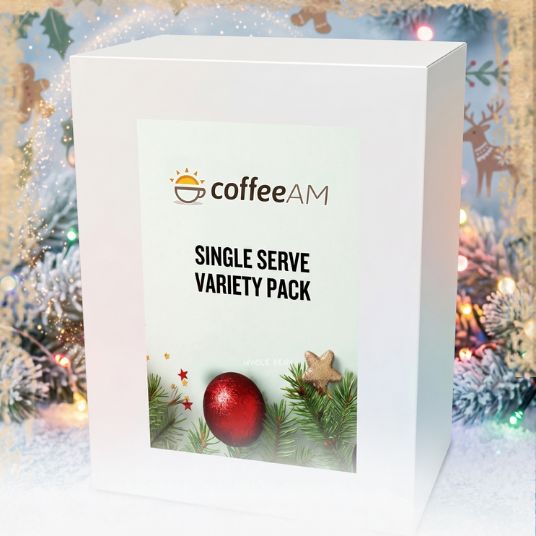A white rectangular box labeled coffeeAM Single Serve Variety Pack, shown against a festive Christmas background with lights, ornaments, and pine branches.