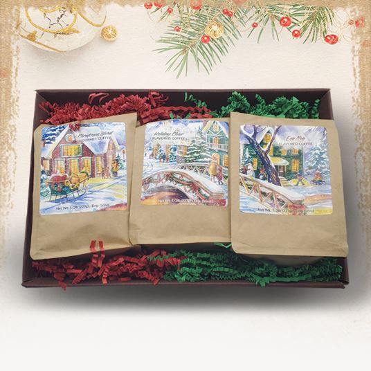 A gift set of three bags of coffee, each with a Christmas-themed illustration, displayed in an open box with holiday decorations.