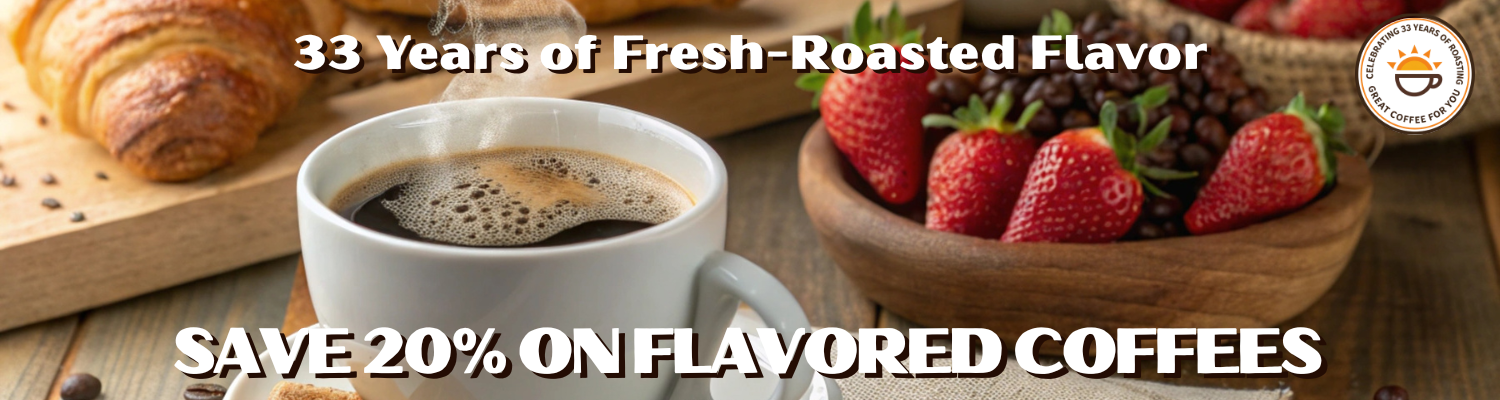 Promotional banner for flavored coffees showing a white mug of black coffee, a croissant on a cutting board, and a bowl of fresh strawberries and berries. Text reads '33 Years of Fresh-Roasted Flavor' and 'SAVE 20% ON FLAVORED COFFEE'.