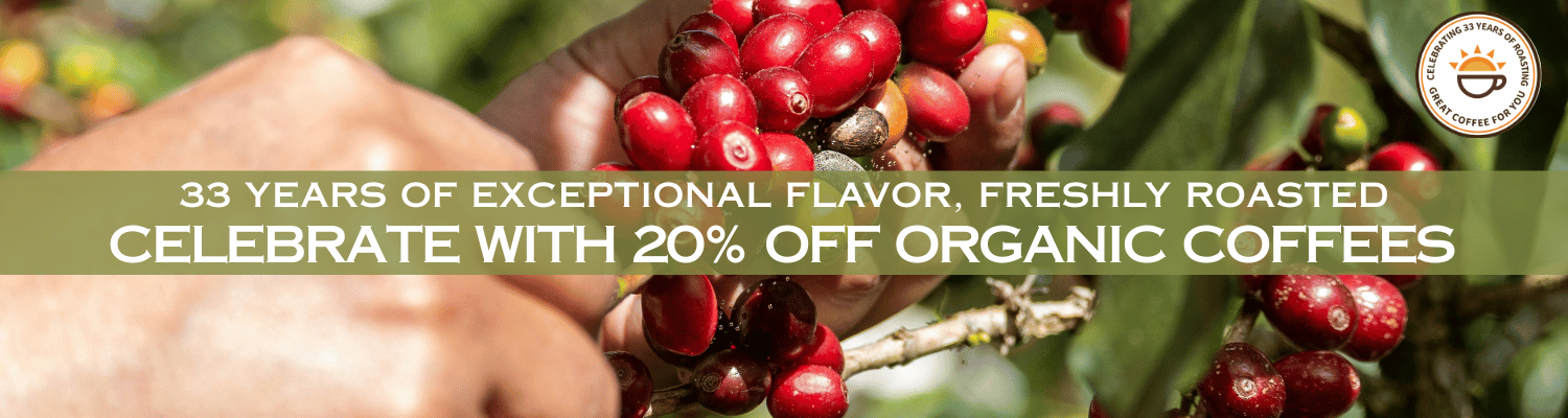 Promotional banner featuring a close-up of hands holding ripe red coffee cherries on a branch, with a dark green banner across the center reading '33 YEARS OF EXCEPTIONAL FLAVOR, FRESHLY ROASTED CELEBRATE WITH 20% OFF ORGANIC COFFEE' and an organic coffee logo in the top right.