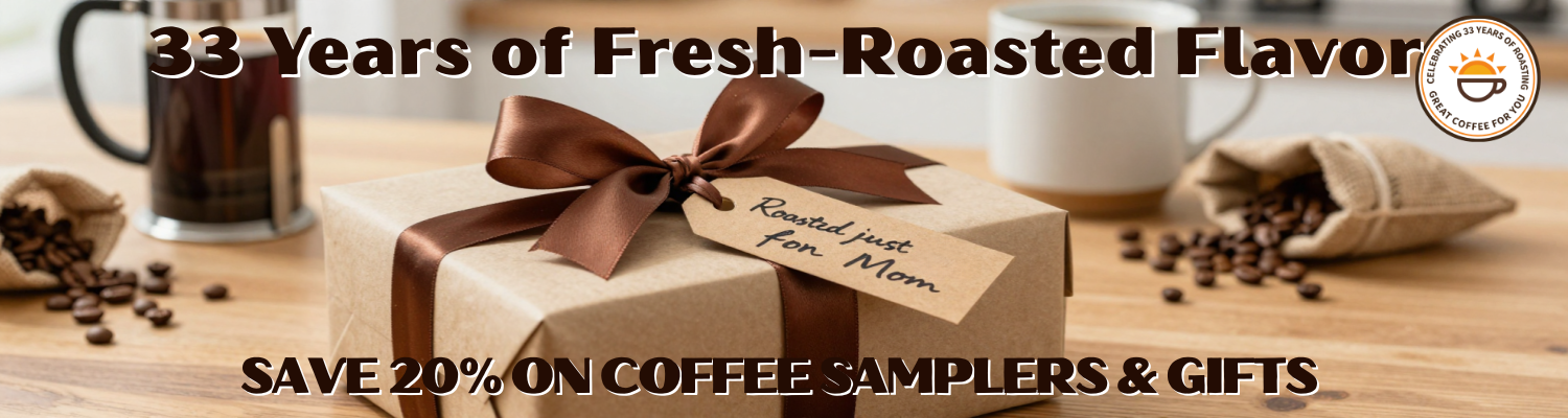 A wrapped coffee gift box with a large brown ribbon sits on a wooden surface with coffee beans, mugs, and a small burlap sack in the background. Text across the top reads '33 years of fresh-roasted flavor' and the bottom reads 'SAVE 20% ON COFFEE SAMPLERS & GIFTS'.