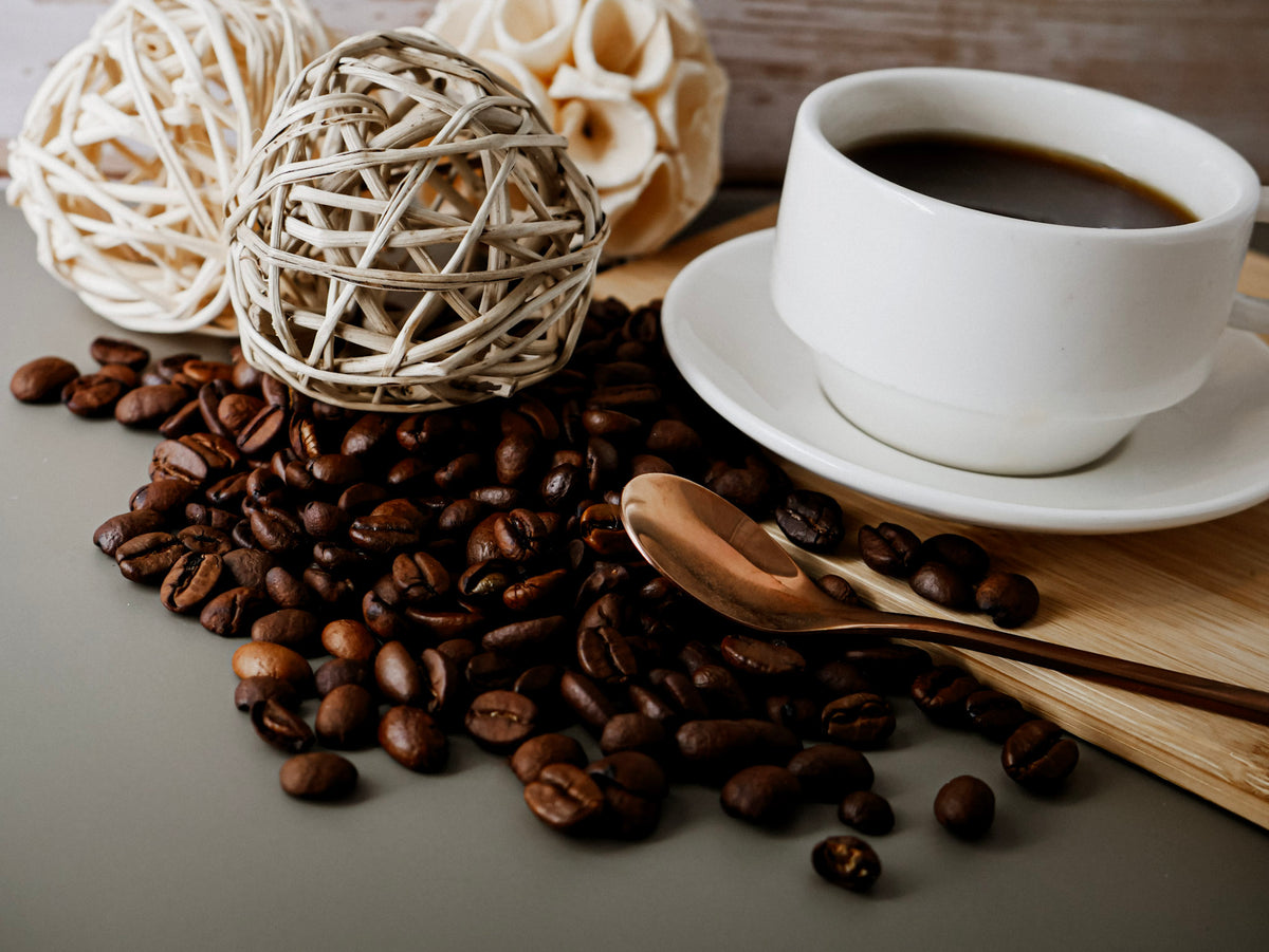 Coffee cup with coffee beans, a golden spoon and some decorative elements