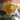 Decorative glass mug filled with tea on a marble surface with dried oranges and tea leaves.