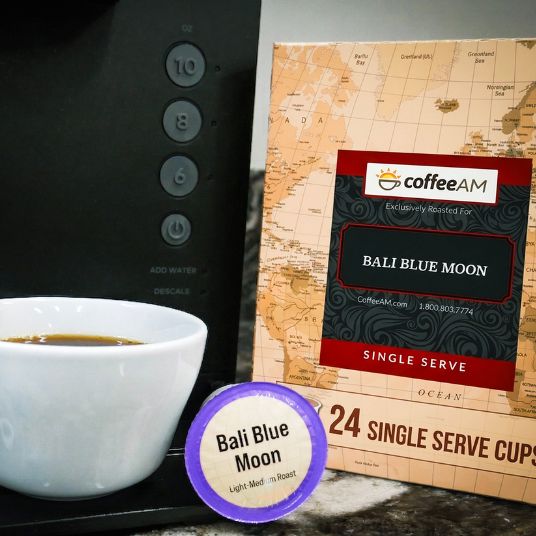 CoffeeAM Bali Blue Moon single serve coffee packaging with a cup of coffee and a coffee machine.