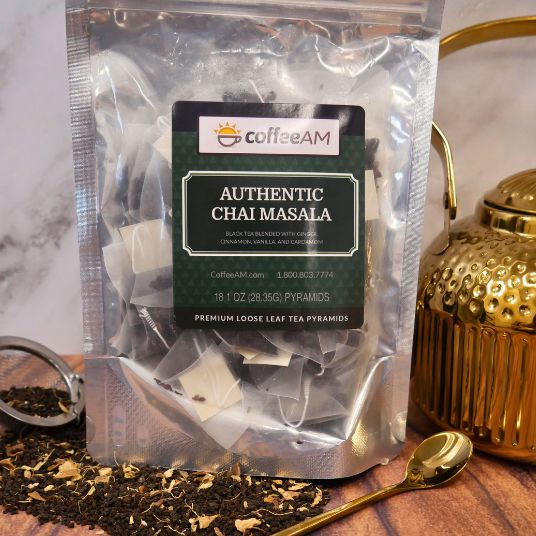 Package of CoffeeAM Authentic Chai Masala tea with loose tea on a wooden surface.