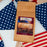 Coffee AM Courage Blend package on a table with American flags in the background