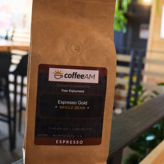 CoffeeAM Espresso Gold whole bean coffee package on a blurred background