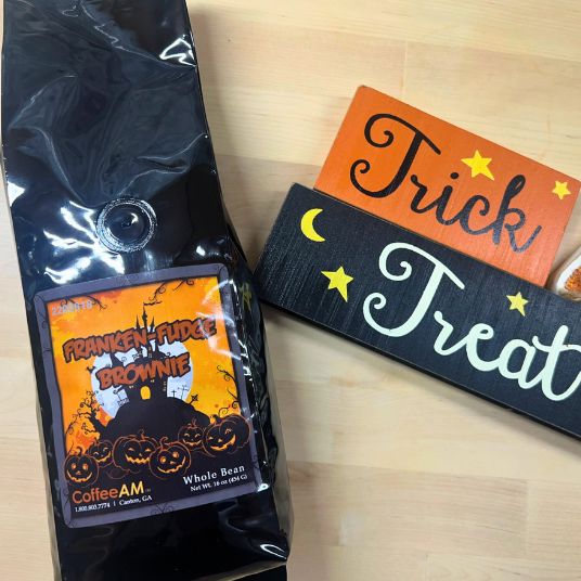 Halloween-themed coffee package and decorative sign on a wooden surface