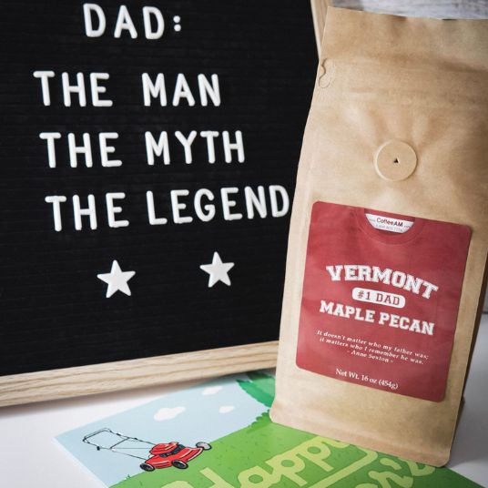 Kraft paper bag with Vermont maple pecan label next to a blackboard with 'Dad: The Man, The Myth, The Legend' text.