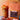 A bag of Coffee AM Nature's Gift Organic Iced Coffee Blend French Press with a black and yellow label, next to an iced coffee drink with a tropical paper umbrella, set against a warm orange background, and surrounded by seashells