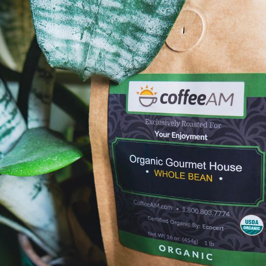 CoffeeAM organic gourmet house whole bean coffee package with a plant in the background
