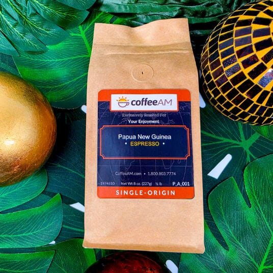 CoffeeAM Papua New Guinea Espresso coffee bag on a decorative background with leaves and ornaments.