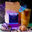 A bag of coffeeAM Paradise Peace cold brew coffee stands next to a tall glass of iced coffee with a colorful paper umbrella, styled with seashells and coffee beans on sand.