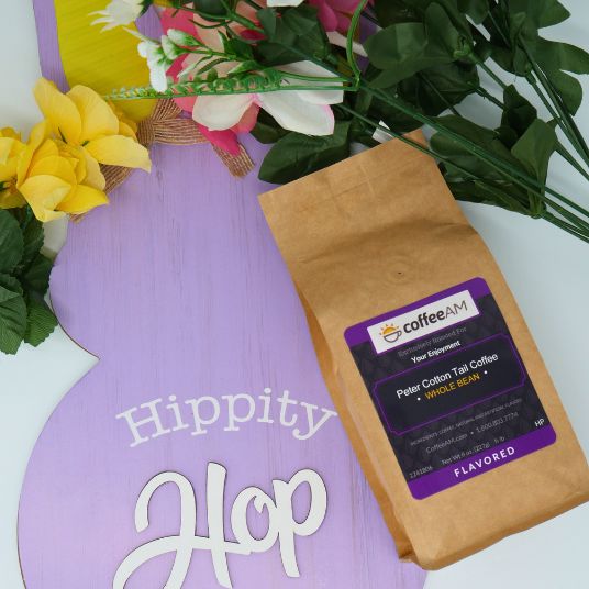 Brown coffee bag with a label on a purple board with 'Hippity Hop' text, surrounded by flowers.