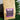 CoffeeAM Rainforest Crunch Coffee package with a purple label on a wooden surface with green leaves in the background.