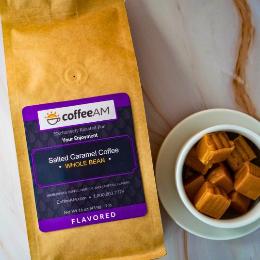 CoffeeAM salted caramel coffee package with a cup of coffee and caramel cubes on a wooden surface.