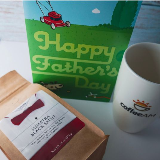 Gift set with 'Happy Father's Day' card, coffee, and a mug on a white surface