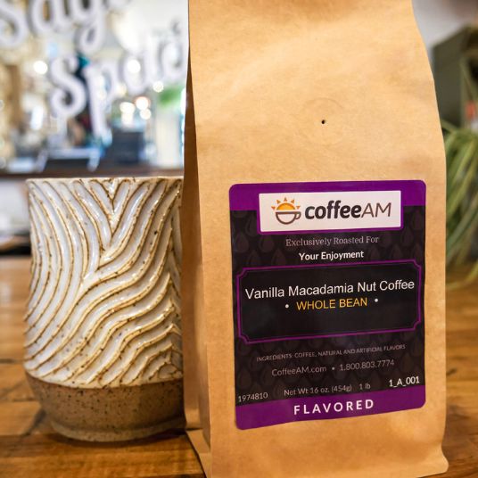CoffeeAM vanilla macadamia nut coffee package on a wooden surface with a blurred background